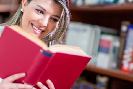Woman reading a book at the library and smiling