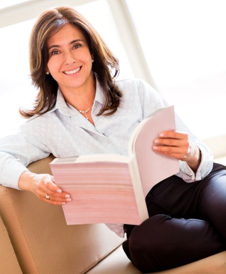 Casual woman reading a book sitting on a sofa