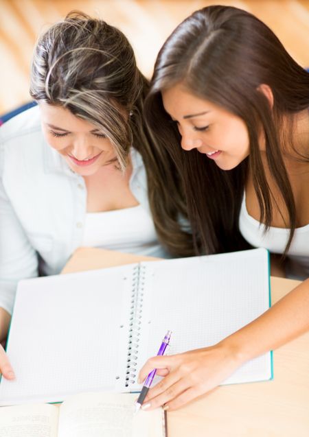 Couple of girls studying together and looking at the notebook