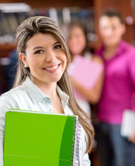 Beautiful female student smiling in front of friends