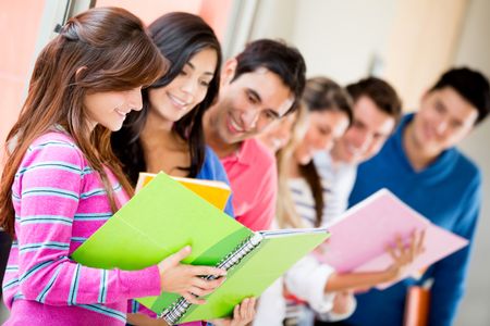 Group of univesity students sharing notes and smiling