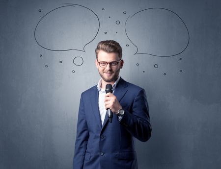 Businessman speaking into microphone with speech bubbles over his head