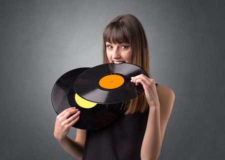 Young lady holding vinyl record on a grey background
