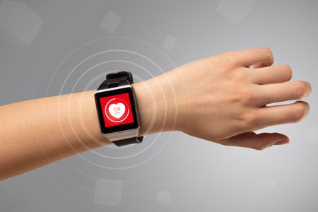Naked female hand with smartwatch and with heart rate icon on the watch