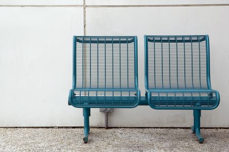 Pair of metal seats by white wall on college campus