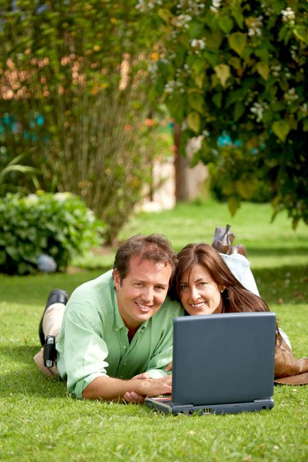casual happy couple on a laptop computer outdoors