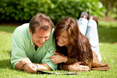 couple relaxing and reading outdoors on the grass