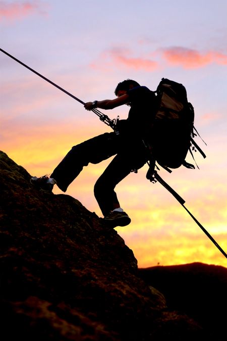 rock climber at sunset going up a mountain