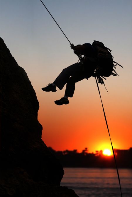 rock climber at sunset time going up a mountain