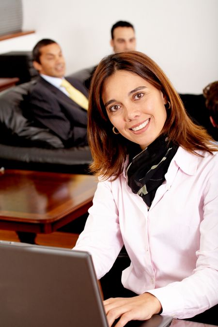 business people in an office working with a businesswoman in the foreground on a laptop computer