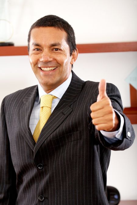 business man smiling doing the thumbs up sign in his office