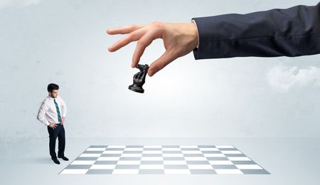 Little businessman thinking about chess strategy with a big hand concept