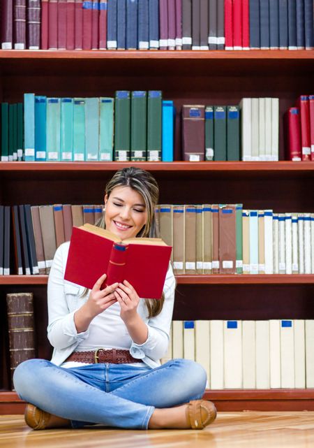 Happy woman reading a book at the library