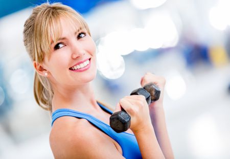Beautiful woman lifting weights at the gym