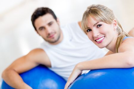 Attractive couple at the gym exercising with Pilates balls