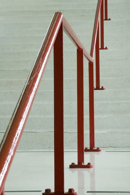 Red handrail along off-white staircase