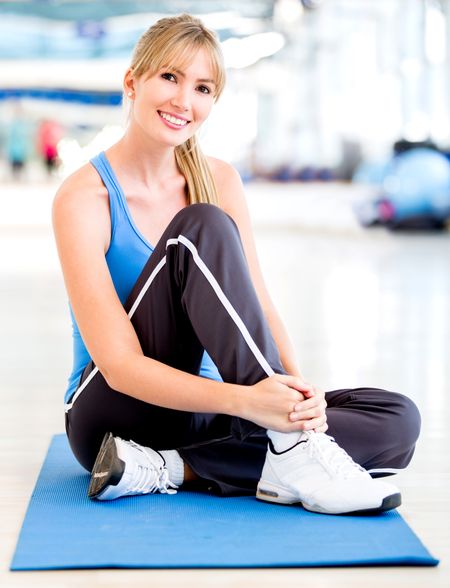 Beautiful woman at the gym sitting on a mat