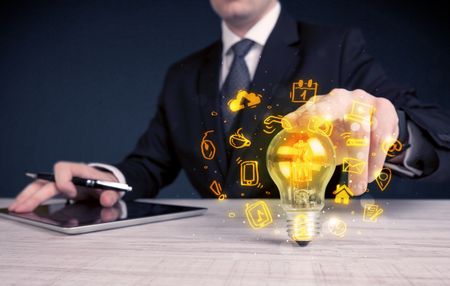 An office salesman promoting his bright ideas concept with illustration of online media and device logos around electric glass light bulb.