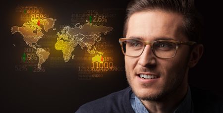 Portrait of a young businessman with a world map and numbers next to him on a dark background