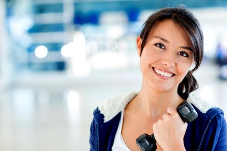 Happy woman at the gym holding a free-weight