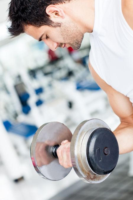 Handsome man working out at the gym lifting weights