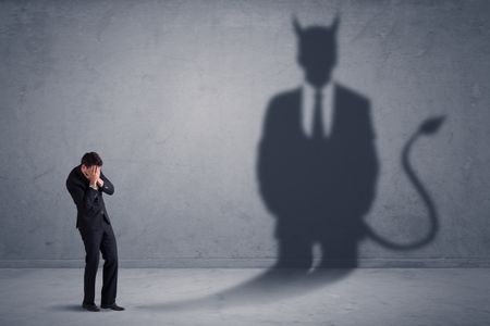 Business man looking at his own devil demon shadow concept background