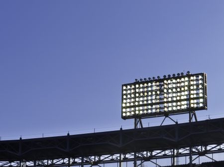 Floodlights over baseball stadium at dusk, with copy space