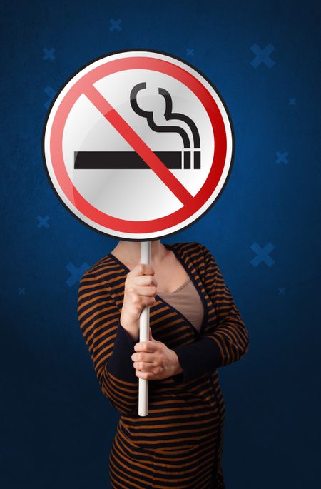 Casual young woman holding round sign with no smoking graphic