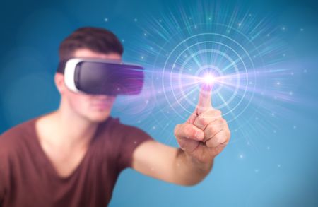 Young impressed man wearing virtual reality goggles with blue circles around his finger