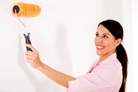Happy woman painting house with a paint roller