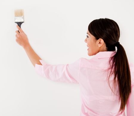 Woman holding a paint brush and painting a wall