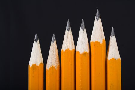 black pencils standing out from the crowd over a black background