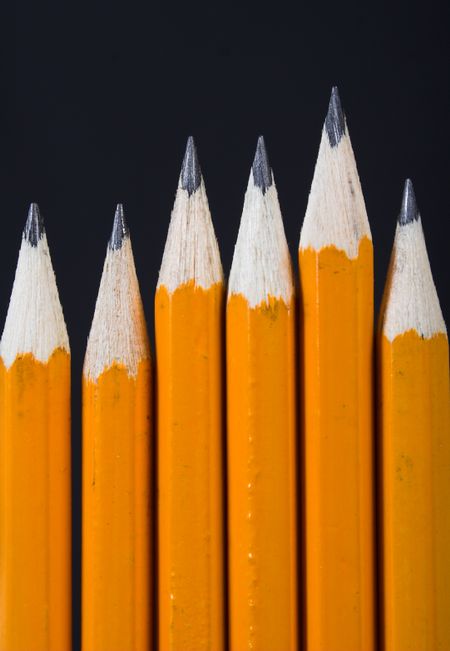black pencils standing out from the crowd over white in vertical layout