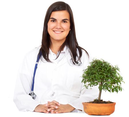 friendly woman doctor smiling with a little tree next to her isolated over a white background