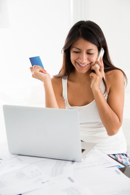 Woman talking to the bank on the phone and buying online