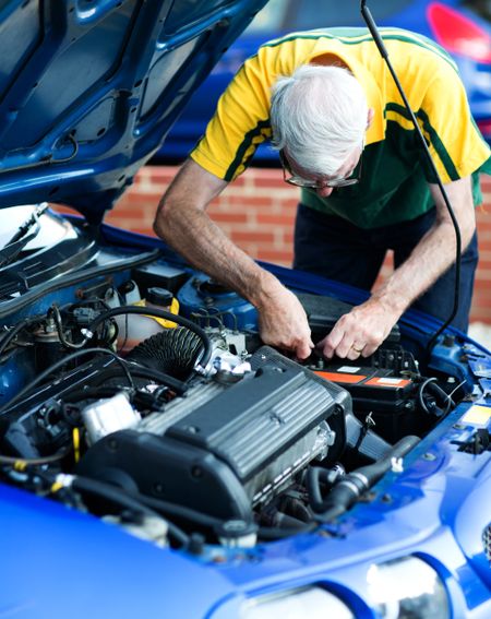 Casual man working on a car engine as a mechanic