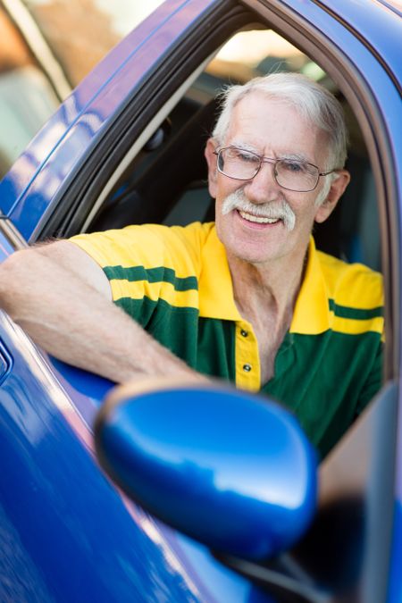 Senior man driving a car and looking happy