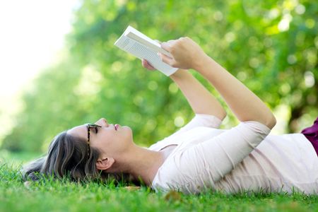 Summer woman reading a book outdoors and relaxing