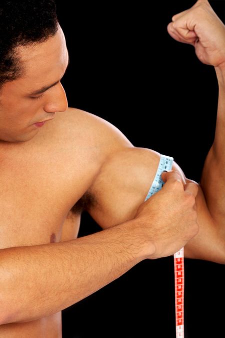 strong man measuring his bicep muscle isolated over a black background