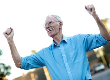 Excited senior man enjoying his retirement with arms up