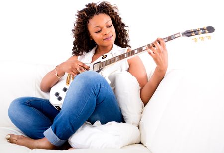 Beautiful woman playing guitar and relaxing at home
