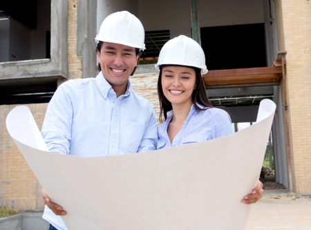 Couple in a construction site looking at their house design