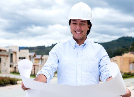 Male architect looking at blueprints in a construction site