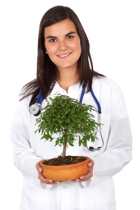 friendly woman doctor smiling with a little tree next to her isolated over a white background