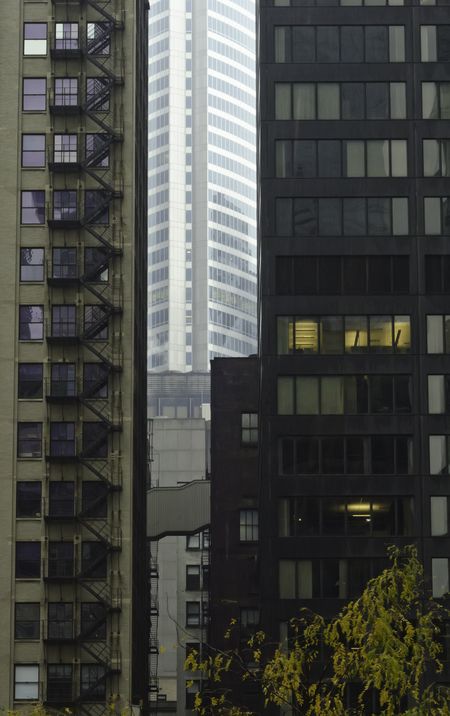 Vision of tomorrow: Bright skyscraper sandwiched between two dark, older office buildings joined by a short pedestrian bridge in downtown Chicago