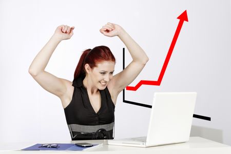 Professional young woman celebrating at work in her office, with a concept, graph displaying a great increase.