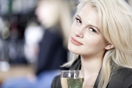 Attractive young woman enjoying a glass of white wine in a wine bar.