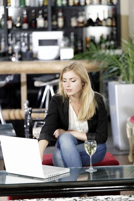beautiful-young-woman-chatting-friends-laptop-116070325 Beautiful young woman chatting with friends on her laptop while enjoying a glass of wine in a bar