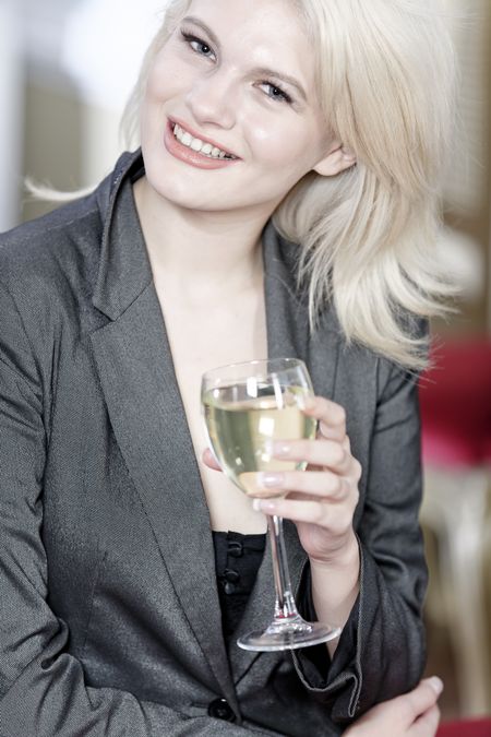 Attractive young woman enjoying a glass of white wine in a wine bar.