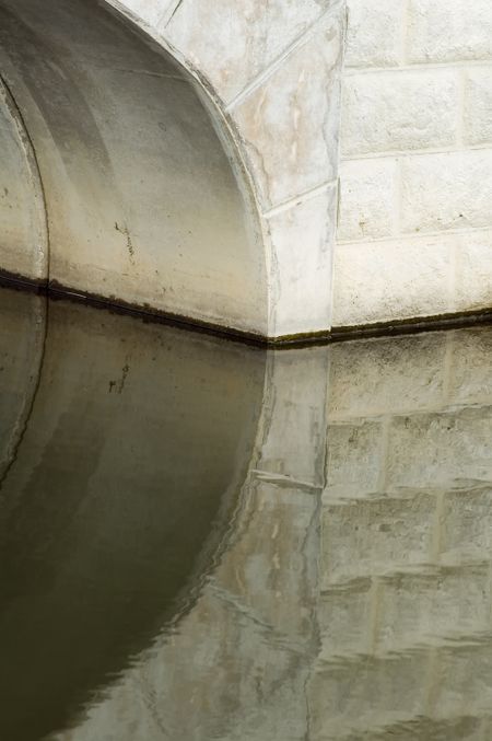 Reflection of footbridge arch over stream